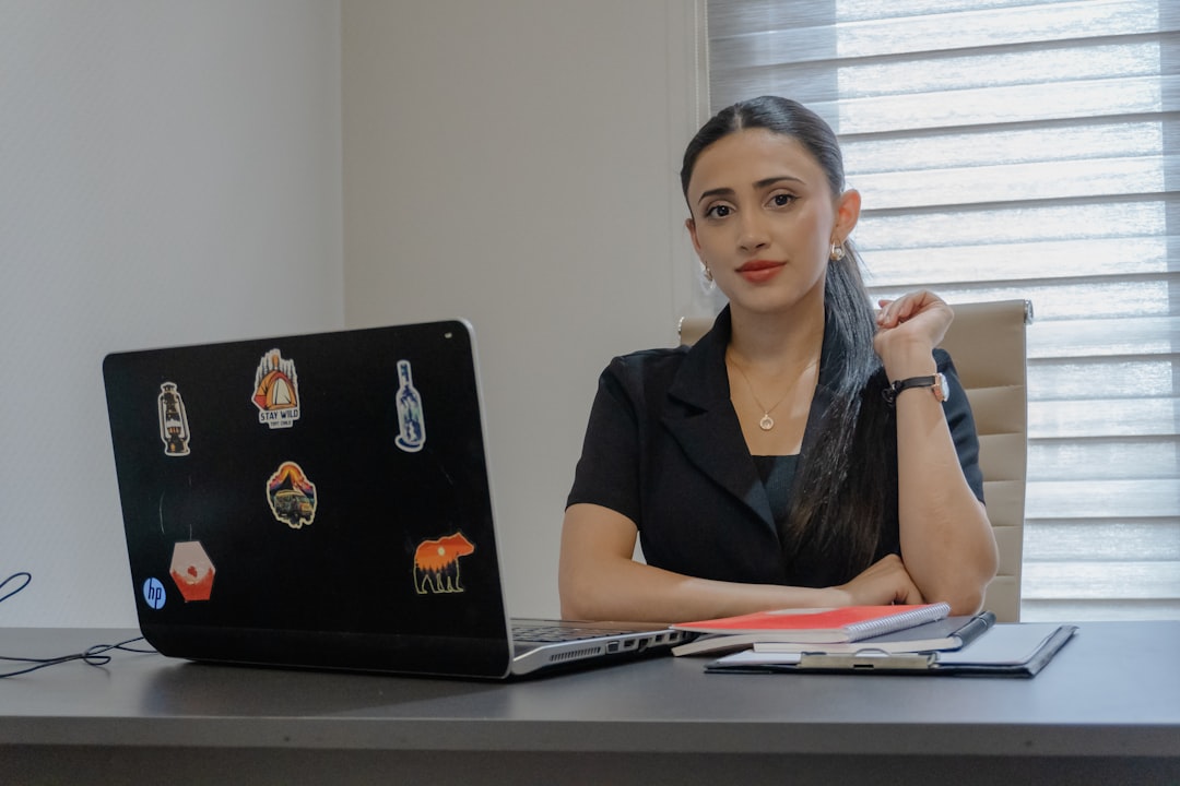 A woman sits at a desk with a laptop.